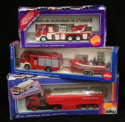 deux camions de pompiers miniatures et un camion miniature dans la boîte