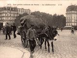 un homme marchant dans la rue avec deux ânes tirant une charrette