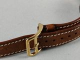 an image of a watch strap with a gold buckle on a white surface