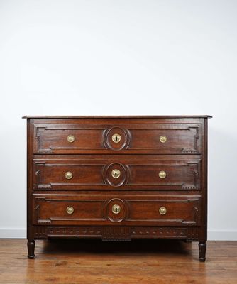 une commode ancienne posée sur un parquet dans une pièce