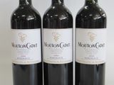 three bottles of red wine are lined up on a white surface