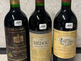three bottles of red wine are lined up on a counter