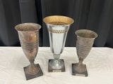 trois vases en argent posés les uns à côté des autres sur une table