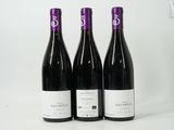 three bottles of red wine sit on a white surface