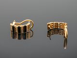 a pair of black and gold earrings on a reflective surface
