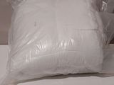 a white pillow on a white table next to a white wall