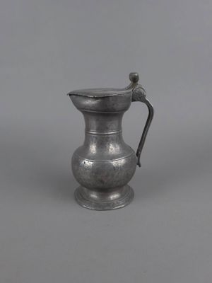 un pichet ancien en argent muni d'une anse, sur fond gris