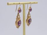 pair of amethorate and gold earrings on a gold stand