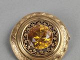 a close up of a gold colored broochle on a gray surface