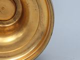 a close up of a gold vase on a white surface