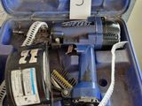 une boîte bleue contenant une perceuse et un cordon