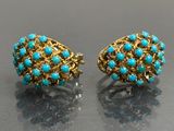 a pair of turquoise and gold earrings on a black surface