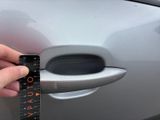 a person holding a measuring tape in front of a car door