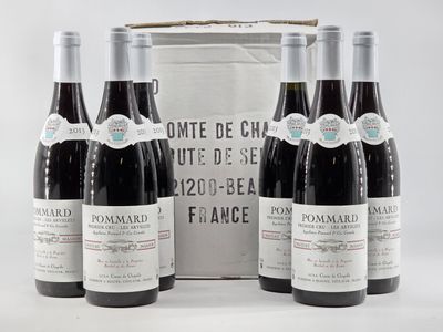 three bottles of red wine sit in front of a white box