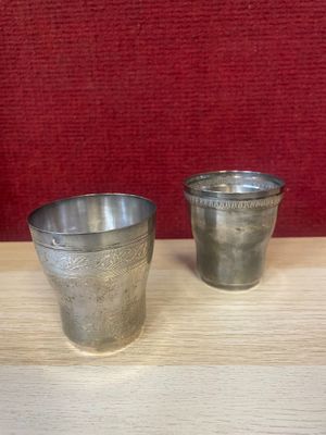 two silver cups sitting on a wooden table next to each other