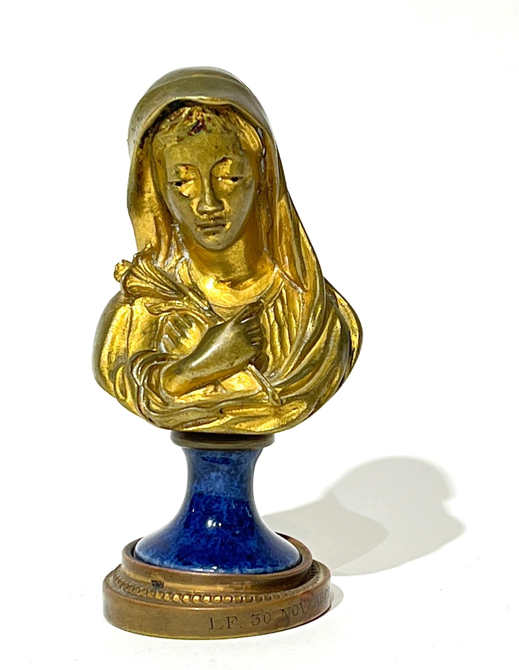 Armand ROBLOT (1890-1983). Buste de sainte tenant un lys en bronze doré, piédouche en porcelaine. Début XXème siècle....