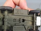 a hand holding a toy army vehicle in the palm of a person ' s hand