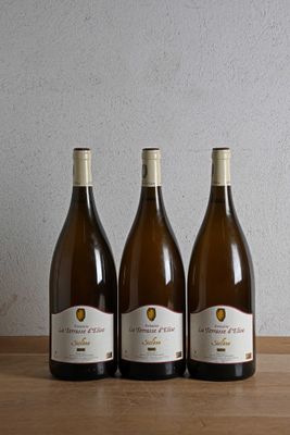 three bottles of wine sit on a wooden table in front of a wall