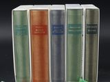 four books are lined up in a row on a black surface