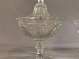 two clear glass bowls with lids on a table