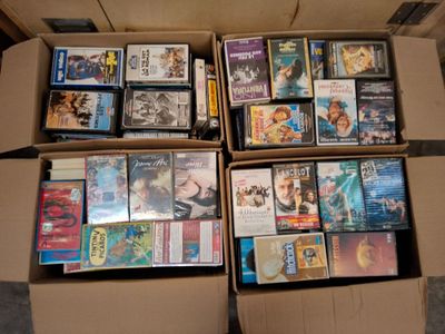 un grand nombre de DVD dans une boîte en carton posée sur le sol
