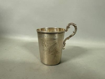 une vieille coupe en argent munie d'une anse, posée sur une surface blanche