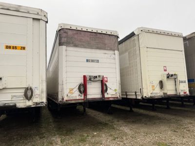 trois semi-remorques garées côte à côte sur un parking