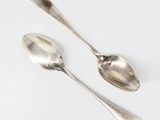 une paire de cuillères en argent posées sur une surface blanche
