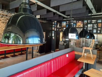 tables and benches in a restaurant with a large lamp hanging from the ceiling