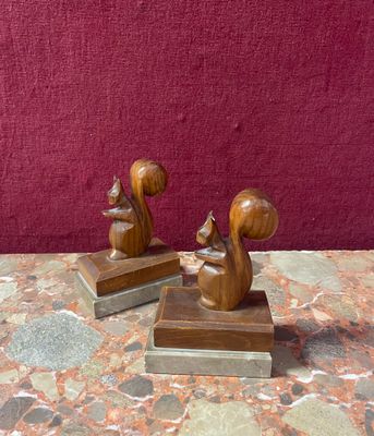pair of wooden squirrel bookends on marble table with red background