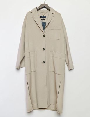 a beige coat hanging on a hanger against a white wall