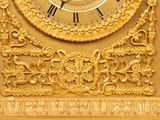 a gold clock with roman numerals on the face