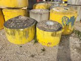 many yellow barrels with graffiti on them in the dirt