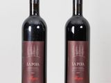 two bottles of red wine sitting on top of a wooden table