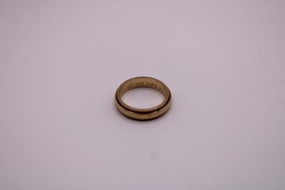 gros plan d'une bague en or sur une surface blanche