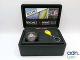 La montre est présentée dans un coffret noir avec un porte-clés jaune.