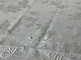 un lit recouvert d'un couvre-lit blanc orné de monogrammes