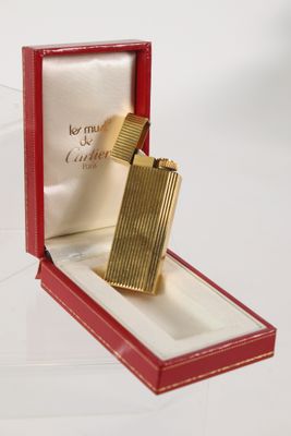 a gold lighter in a red box on a white surface