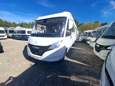 un bus blanc garé sur un parking aux côtés d'autres véhicules