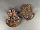 pair of antique brass rooster door knockets on a gray background