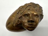 bronze sculpture of a woman ' s head on a white surface