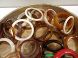 many different colored rings in a bowl on a table