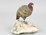 figurine représentant un oiseau perché sur un rocher, posée sur un fond blanc