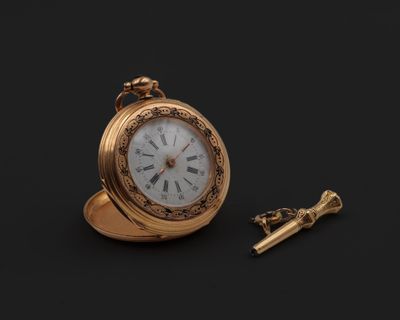 une montre de poche en or et une clé sur fond noir