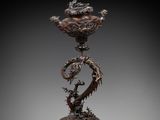 a bronze vase with two birds on top of it