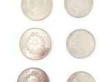 six different types of silver coins on a white surface