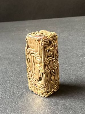 un objet doré posé sur une table, sur fond noir