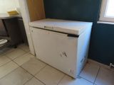 un petit réfrigérateur blanc dans le coin d'une pièce