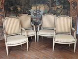 trois chaises blanches placées devant un mur sur lequel est accrochée une peinture