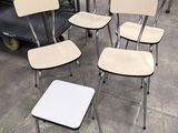 plusieurs chaises et une table dans un entrepôt, avec un chariot à l'arrière-plan